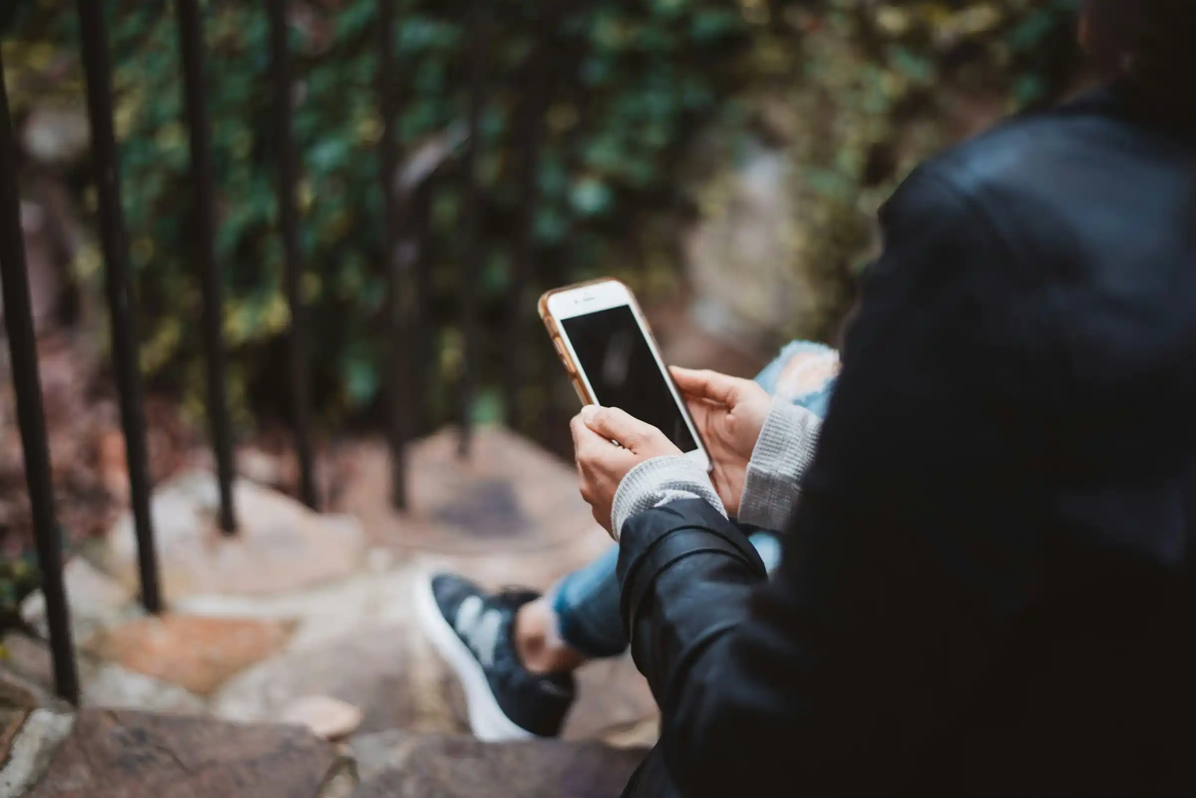 Woman sitting on outdoor stairs holding a smartphone